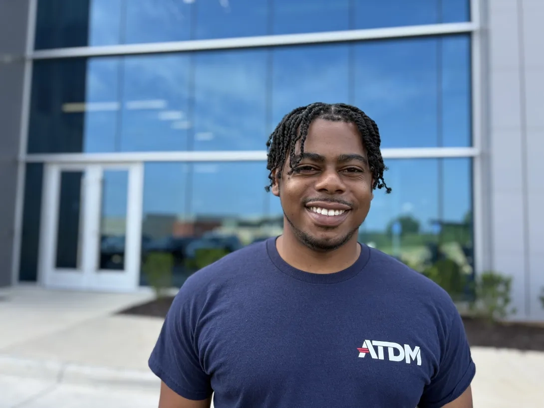Man, smiling, stands in front of building