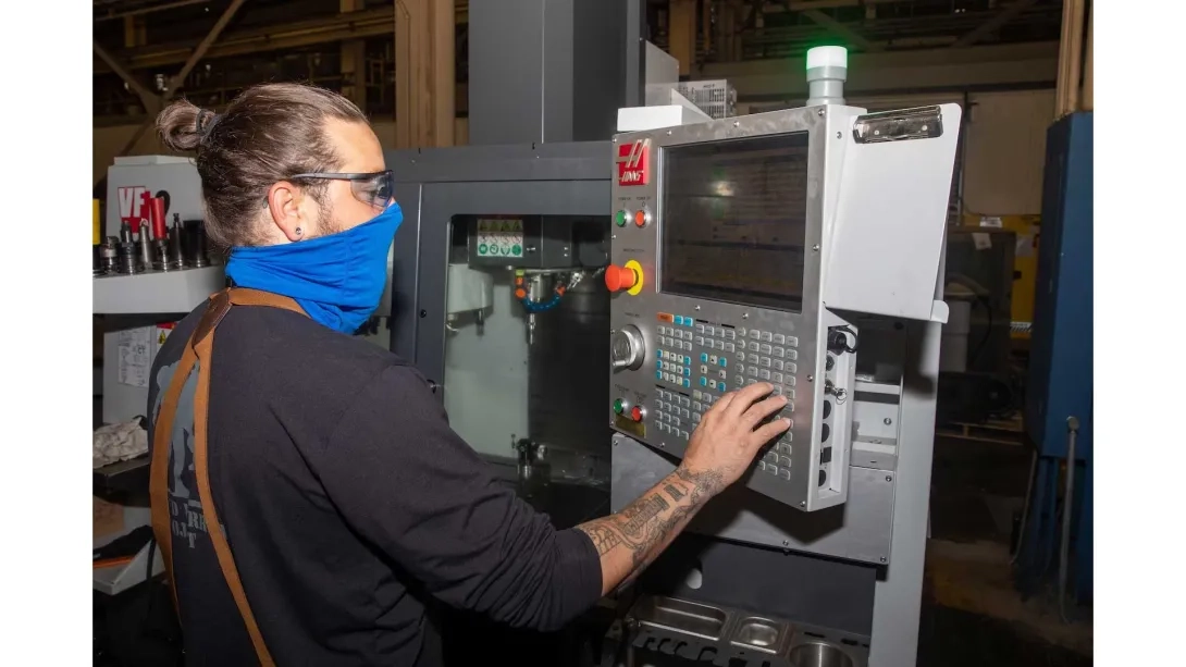 Man wearing a mask and using a CNC machine
