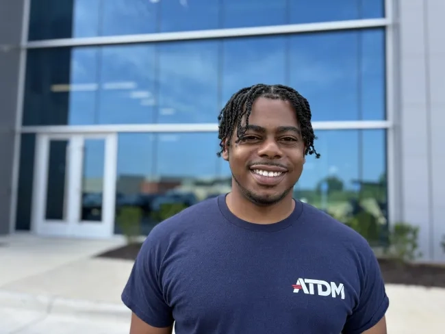 Man, smiling, stands in front of building