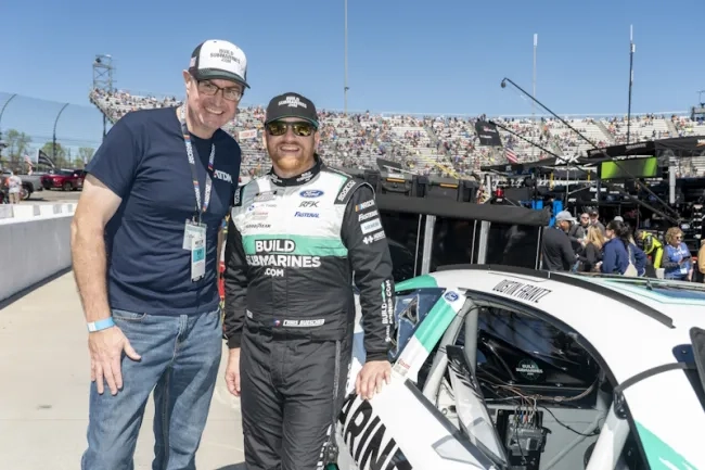 Two men standing beside a racing car at Martinsville Speedway