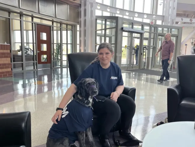 Woman seated with a dog beside her.